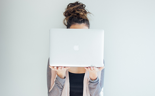 Girl with a bun holds laptop open